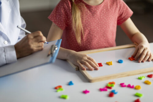Little girl exercising with alphabet board during session with child development specialist